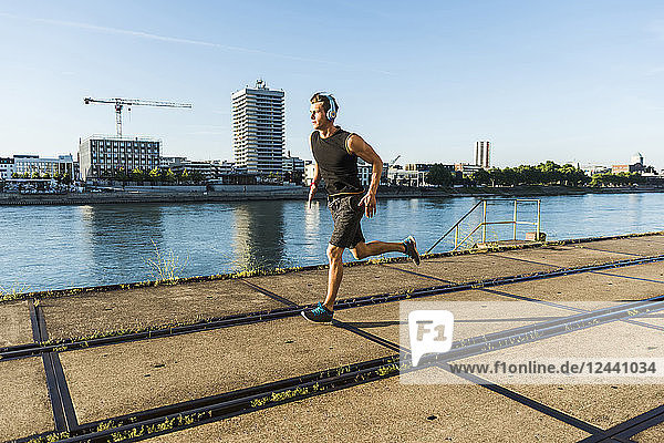Young athlete jogging in the city at the river