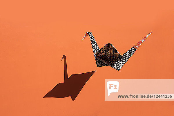Origami crane  orange background  shadow  copy space