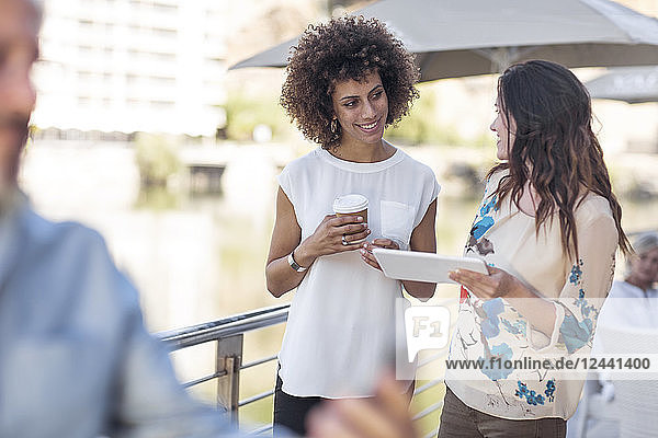 Businessman and woman having a meeting outdoors  using digital tablet