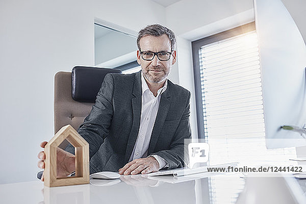 Portrait of businessman at desk in office with architectural model