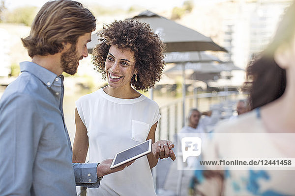 Businessman and woman having a meeting outdoors  using digital tablet