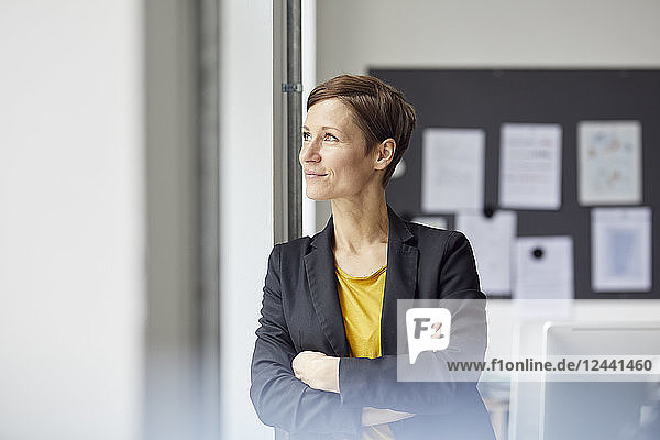 Attractive businesswoman standing in office with arms crossed