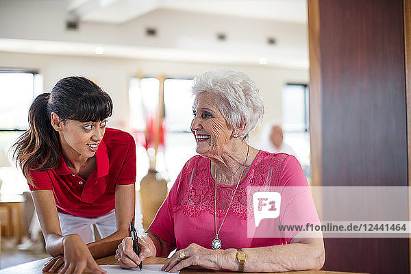 Senior woman signing a contract  nurse helping her