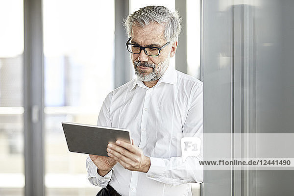 Businessman standing at the window using tablet