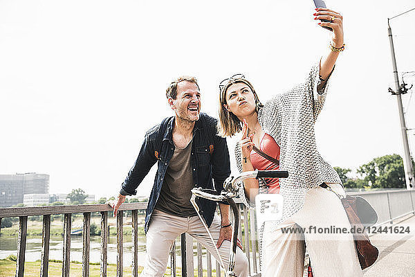 Happy couple taking a selfie on a bridge