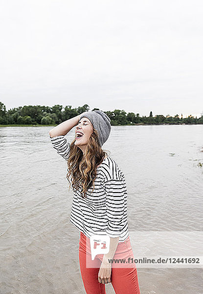 Laughing woman wearing wooly hat at a river