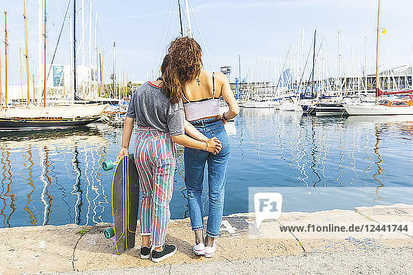 Young woman and teenage girl with a skateboard standing at marina