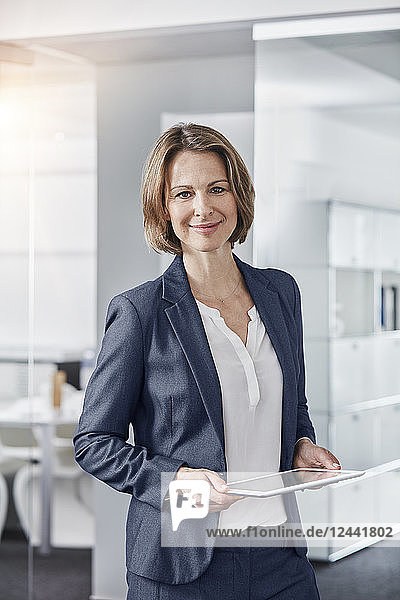 Portrait of smiling businesswoman holding tablet in office
