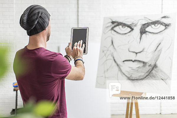 Artist taking photo of his drawing in studio