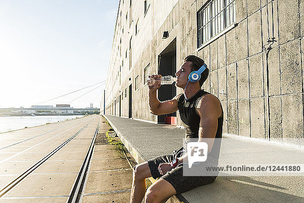 Young athlete wearing headphones  sitting on a wall