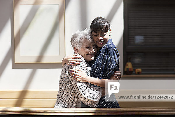 Nurse embracing senior woman in retirement home