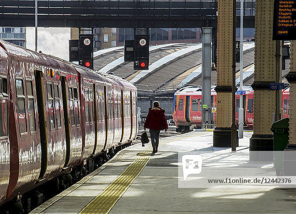Bahnsteig des Bahnhofs Waterloo mit einem Pendler  der neben dem Zug hergeht; London  England