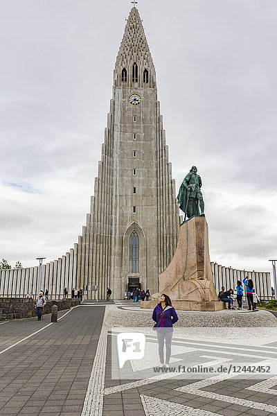 Eine Touristin posiert vor der ikonischen Hallgrimskirkja  der höchsten Kirche Islands; Reykjavik  Island