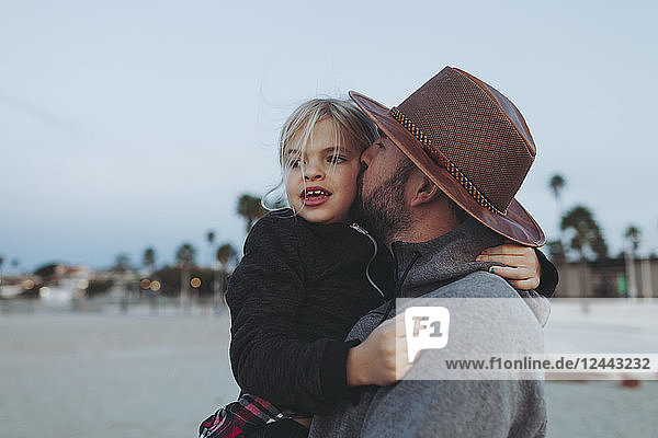 Ein Vater und seine Tochter haben einen zärtlichen Moment  der Vater hält seine Tochter in einer Umarmung an einem Strand in der Abenddämmerung; Long Beach  Kalifornien  Vereinigte Staaten von Amerika