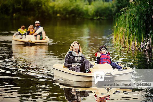 A mother and father take their three sons paddle boating on a lake in a city park  Edmonton  Alberta  Canada