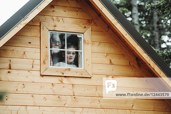 Mother and daughter looking out a playhouse window; Alberta  Canada