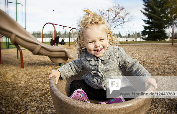 Ein niedliches junges Mädchen  das sich auf einem Spielplatz während der Herbstsaison in einer Untertasse dreht  Spruce Grove  Alberta  Kanada