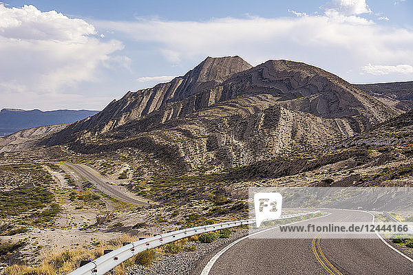 Kurvenreiche Straße durch die Wüste mit einem seltsam geformten Berg; Neuquen  Argentinien