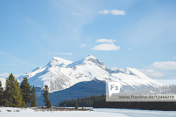 Snow on the lake and snow-capped rugged mountains peaks in Jasper National Park; Alberta  Canada