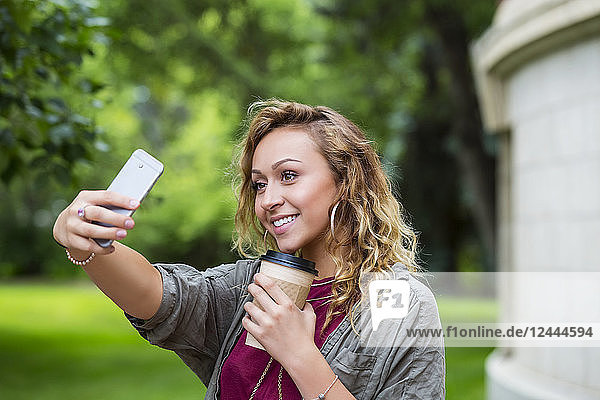 A beautiful female university student taking a self-portrait with her smart phone on the campus  Edmonton  Alberta  Canada