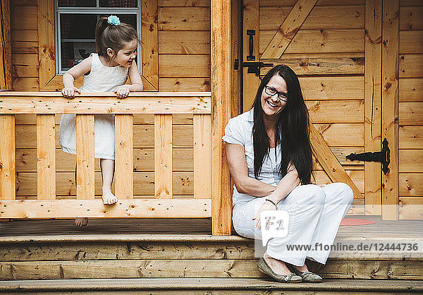 Portrait of a mother and daughter with a wooden playhouse; Alberta  Canada