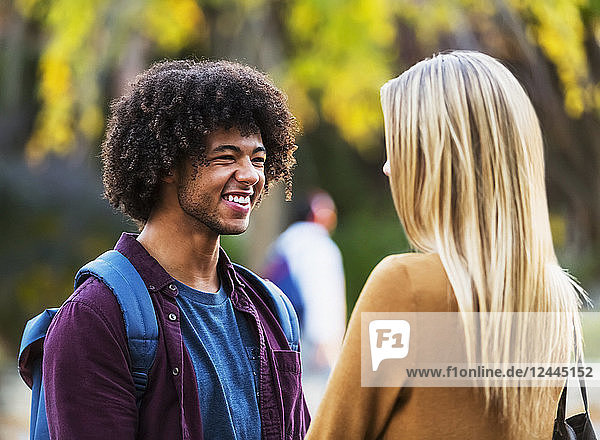 Boyfriend and girlfriend stand having a conversation and smiling while on the grounds of a university campus  Edmonton  Alberta  Canada