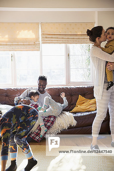 Verspielte multiethnische Familie im Pyjama im sonnigen Wohnzimmer