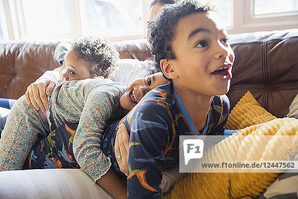 Verspielte  liebevolle junge Familie im Pyjama auf dem Wohnzimmersofa
