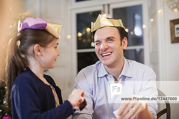 Glücklicher Vater und Tochter mit Weihnachtskronen aus Papier lachen