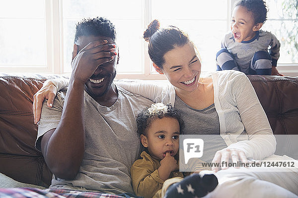 Lachende  glückliche multiethnische Familie auf dem Wohnzimmersofa