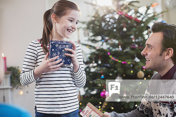 Vater und Tochter mit Geschenken vor dem Weihnachtsbaum