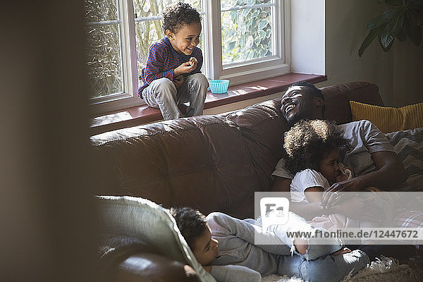 Happy father and children cuddling on living room sofa