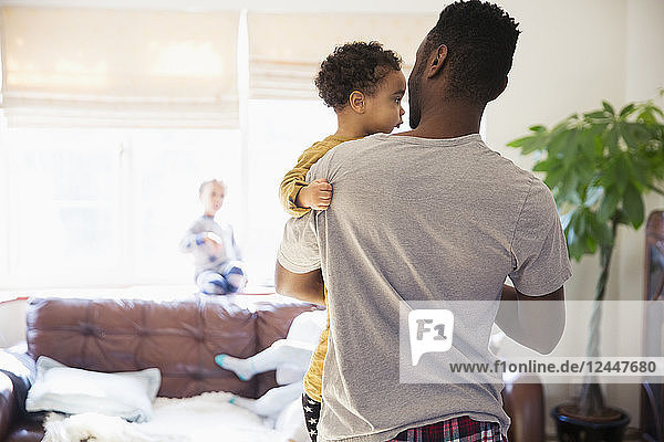 Father holding baby son in living room