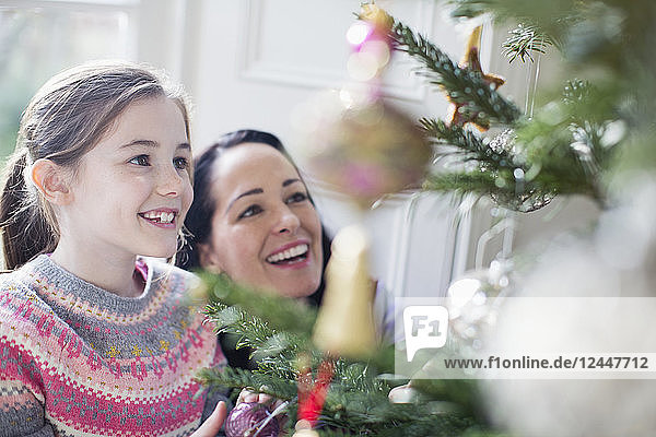 Glückliche Mutter und Tochter beim Schmücken des Weihnachtsbaums