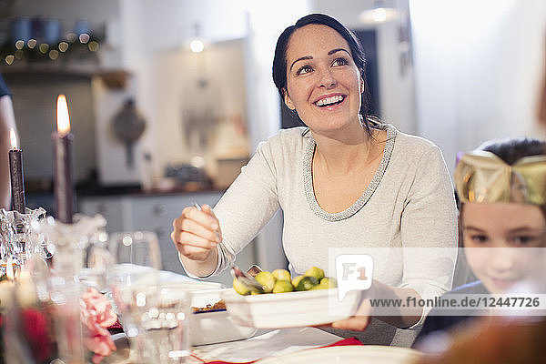Smiling woman serving Brussels sprouts at Christmas dinner table
