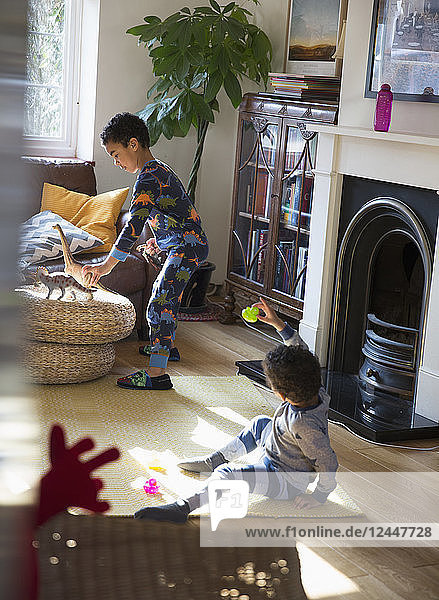 Brüder im Schlafanzug spielen mit Spielzeug im Wohnzimmer