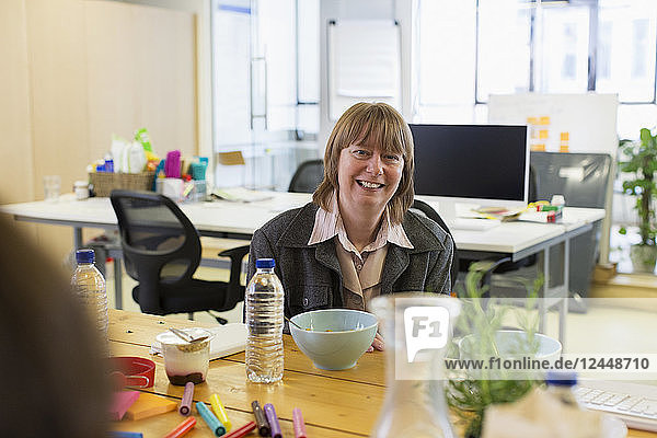 Portrait smiling  confident businesswoman eating in office