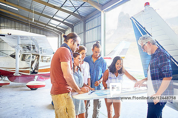 Friends planning trip at map in airplane hangar