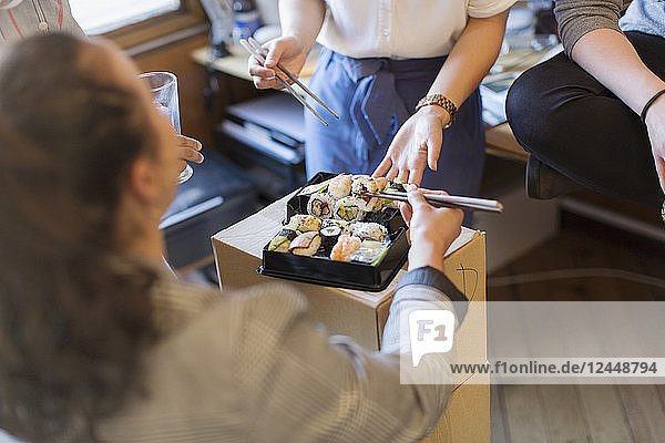 Business people eating sushi in office