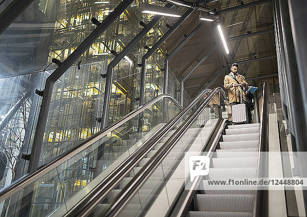 Businessman with suitcase on urban escalator