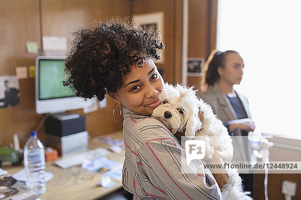 Portrait smiling creative businesswoman with cute dog in office