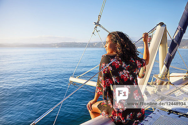 Serene young woman relaxing on sunny catamaran  looking out at blue ocean