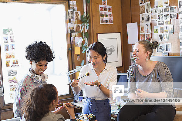 Creative female designers eating sushi in office