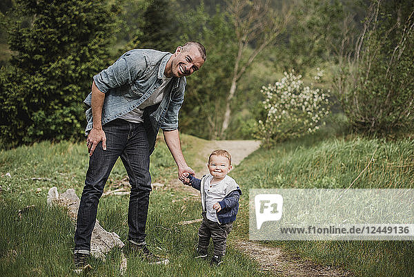 Portrait father and baby son walking on grassy path