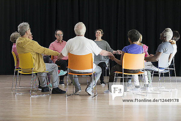 Active seniors meditating  holding hands in circle
