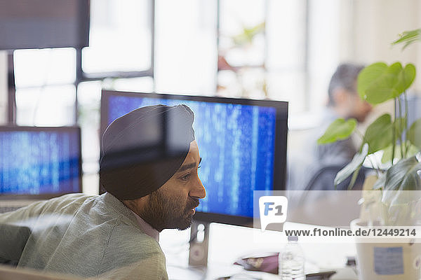 Indian computer programmer in turban working in office