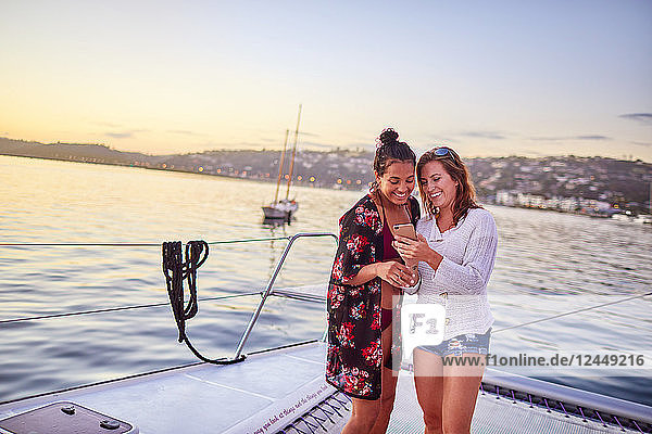 Young women using smart phone on catamaran