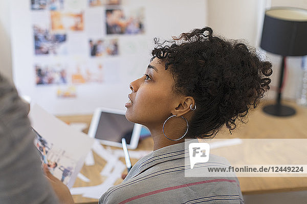 Attentive creative female designer reviewing proofs in office