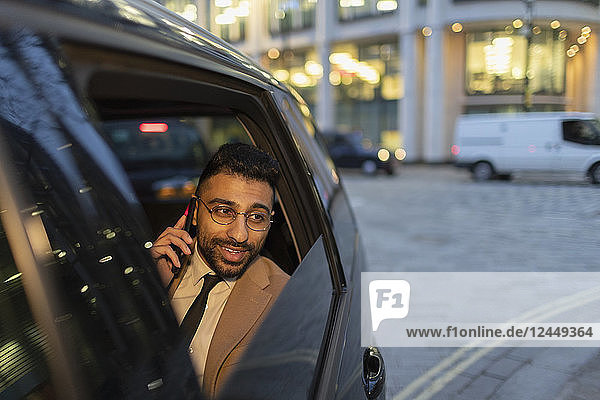Businessman talking on smart phone in crowdsourced taxi