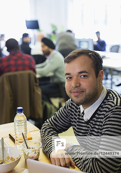 Portrait confident businessman eating breakfast in office